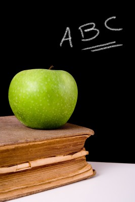 An apple on top of a book next to a chalk board 